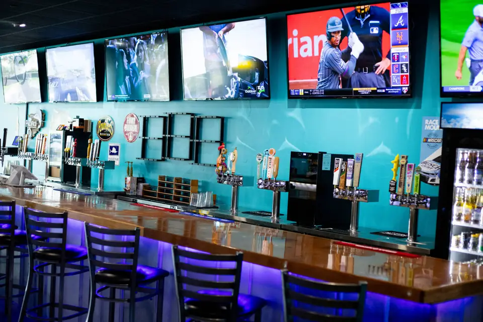 TVs over the long bar with blue under-bar lighting