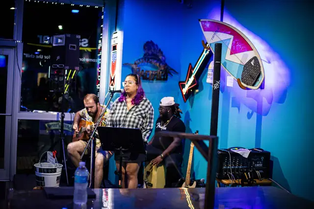 A trio performing under the turquoise walls and surfboard art