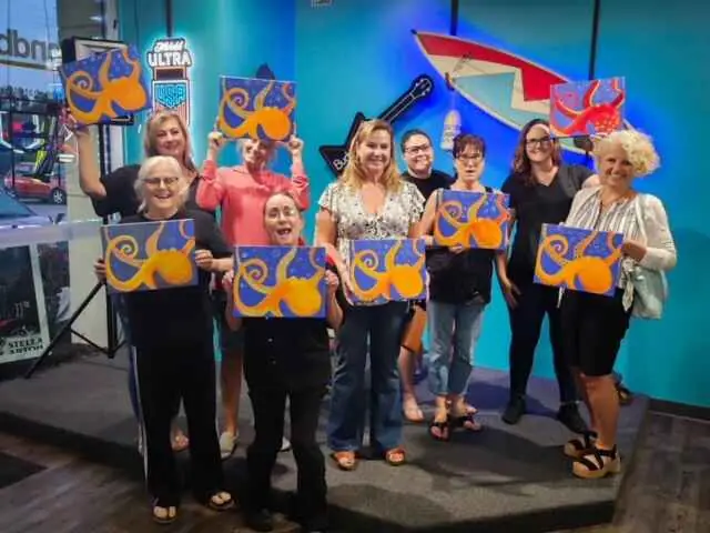 A group of guests holding up their finished paintings